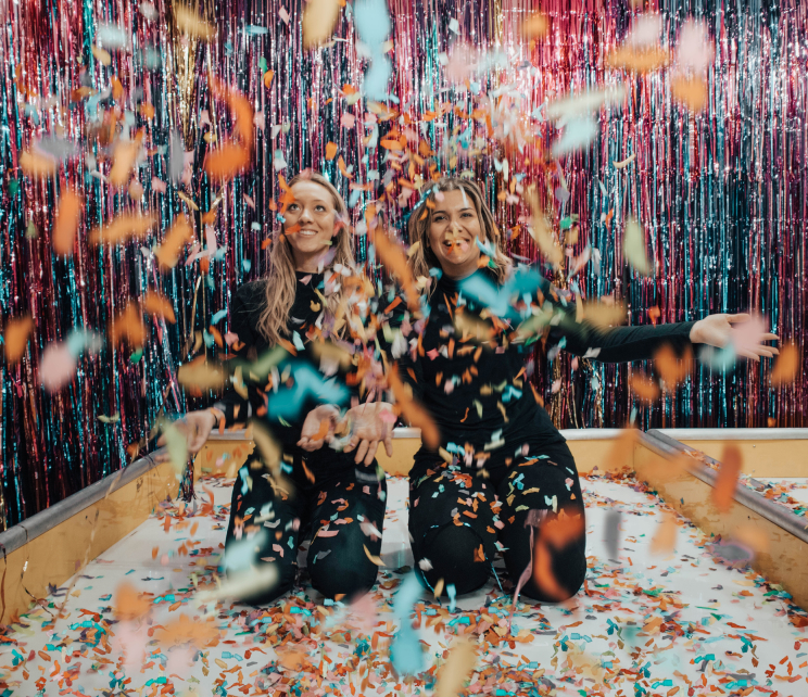 Two happy women in a room with confetti